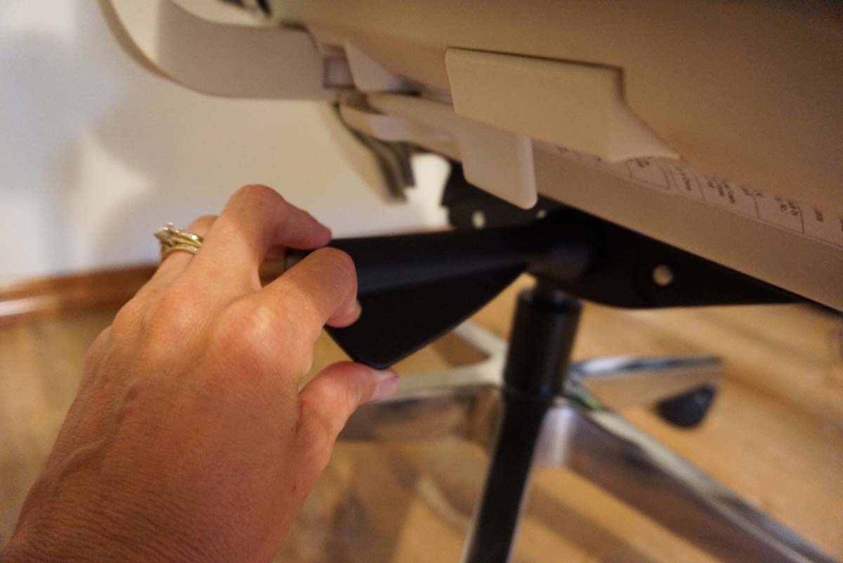 A close-up of a person's hand using the adjustment feature of the Branch ergonomic chair