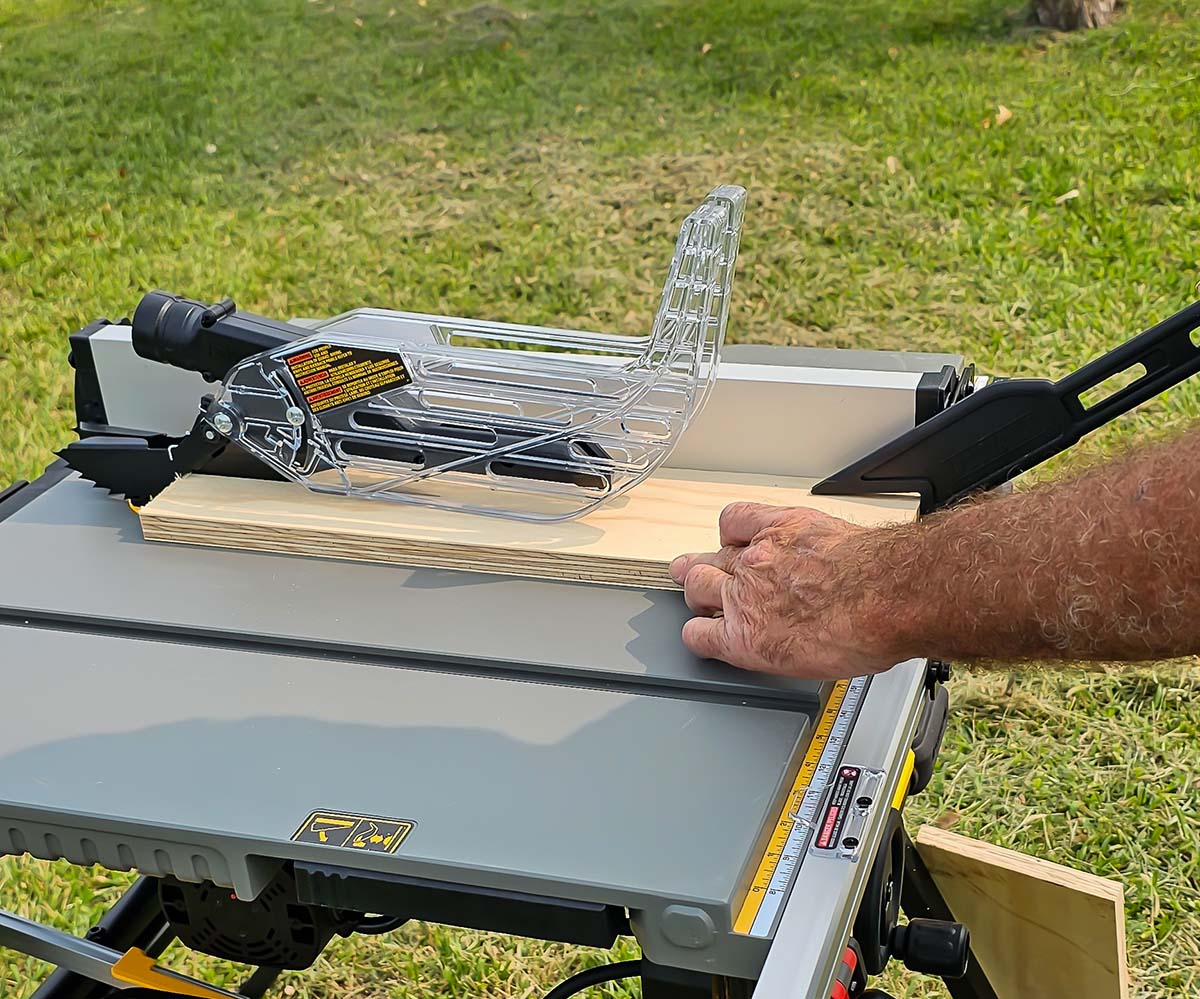 A person using the DeWalt 10-inch table saw to cut a piece of wood