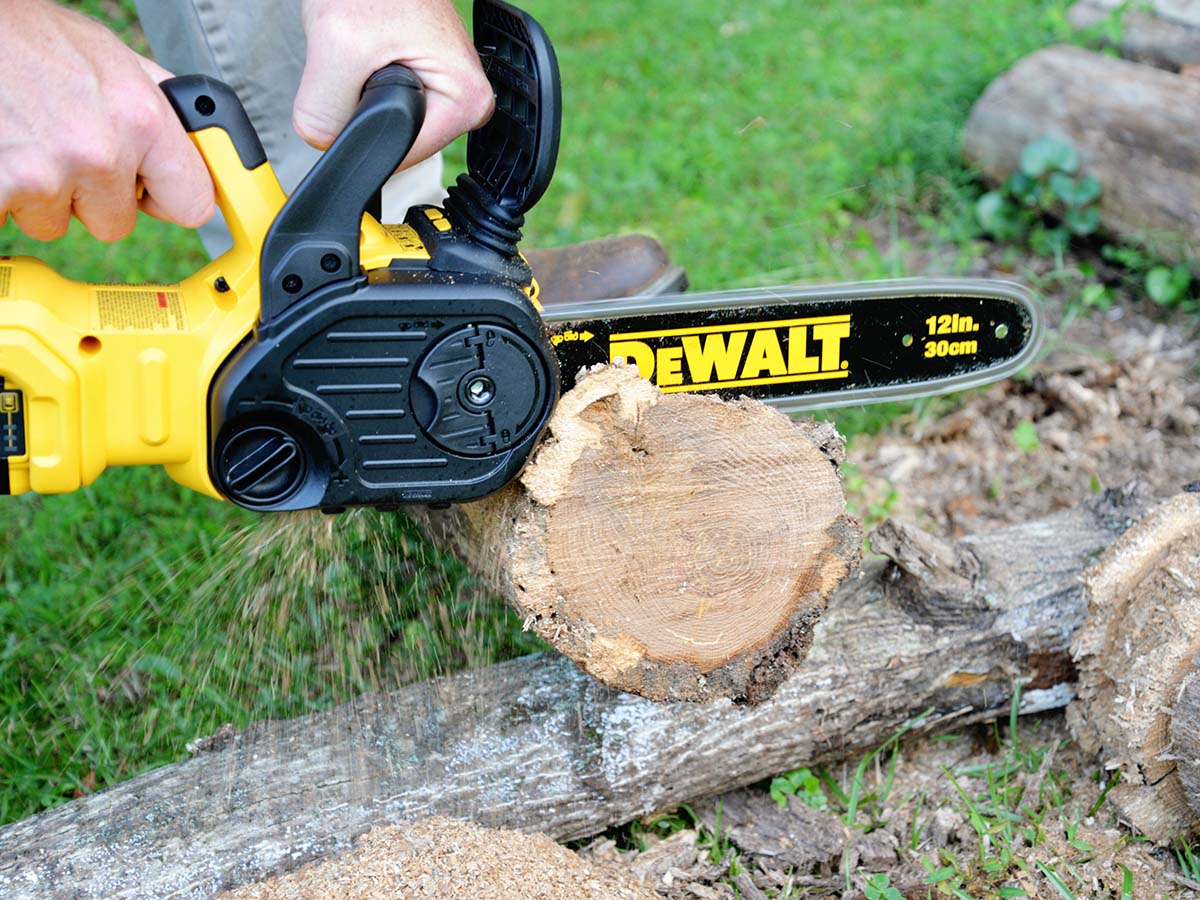 Someone using the DeWalt 20V chainsaw to cut the end off a log