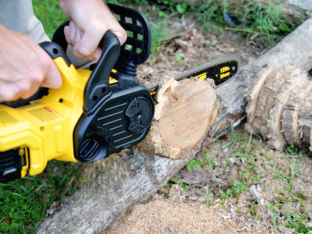 Person using the DeWalt 20V chainsaw to cut the end off a log