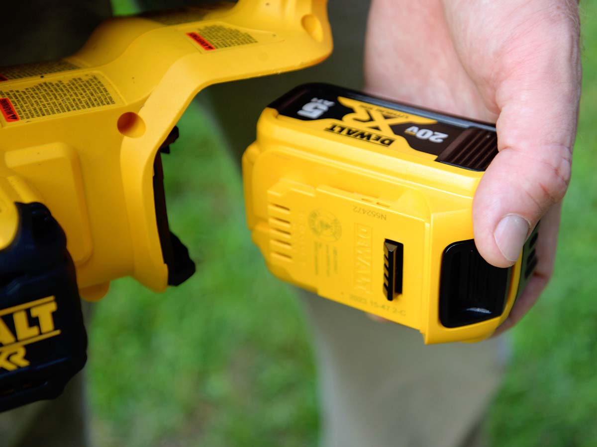 Someone putting a new battery on the DeWalt 20V chainsaw