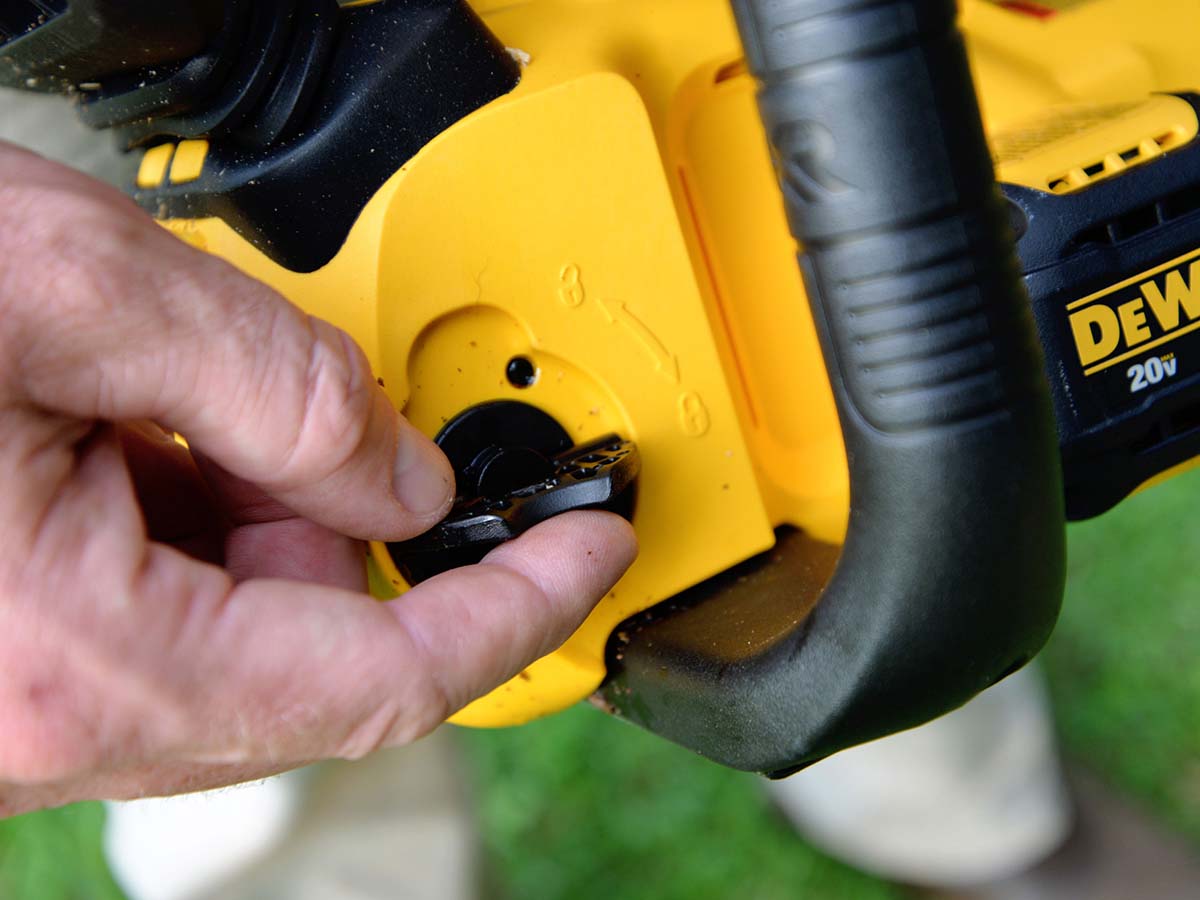 Person using dial to unlock the DeWalt 20V chainsaw