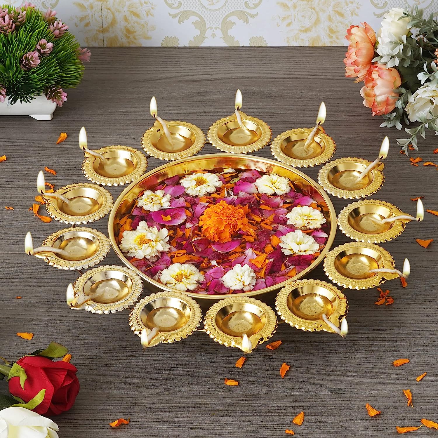gold decorative urli bowl with flowers and diya for diwali celebration
