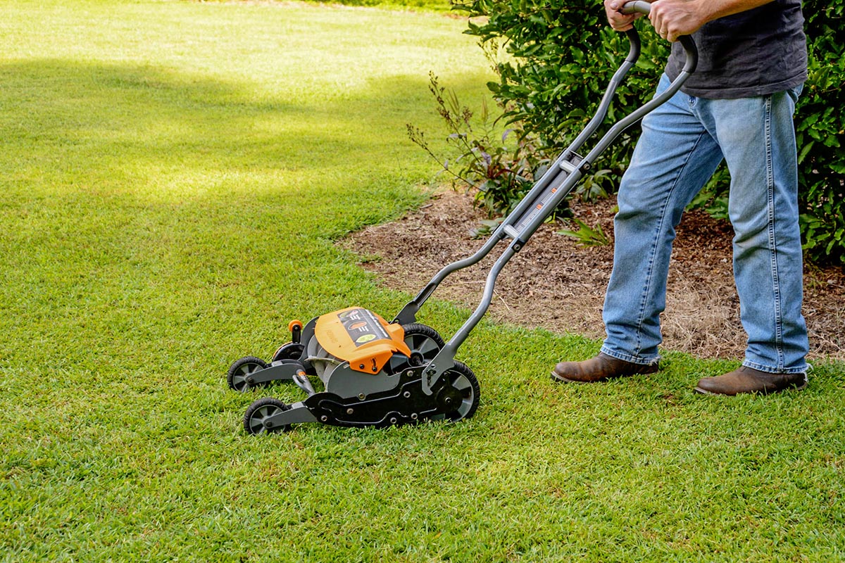 A person using the Fiskars StaySharp Max reel mower to mow their lawn