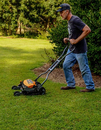 A person using the Fiskars StaySharp Max reel mower to mow their lawn