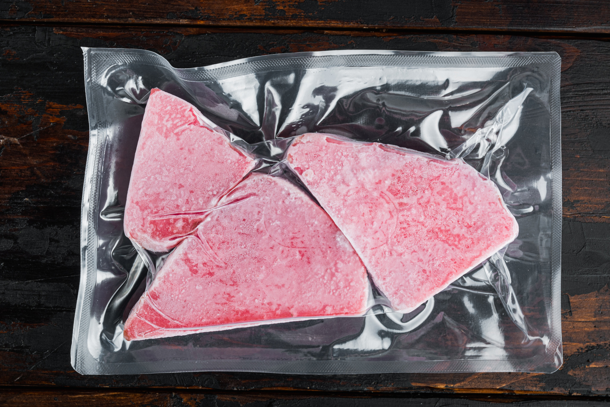 Freeze-dried and vacuum-sealed tuna steak on a dark wooden surface