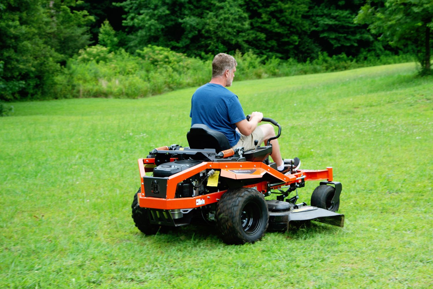 A person mowing their lawn with the Husqvarna XCite 350 zero turn riding mower