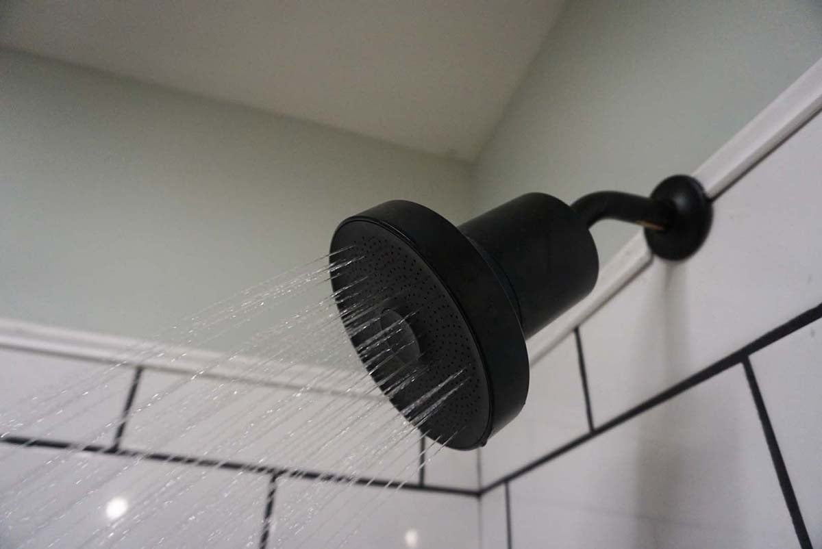 A close-up of the Jolie shower head running in a tiled shower