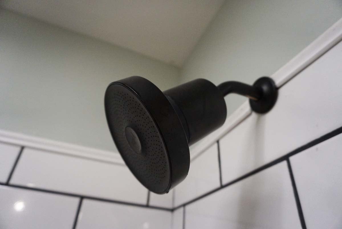 A close-up of the Jolie shower head installed in a tiled shower