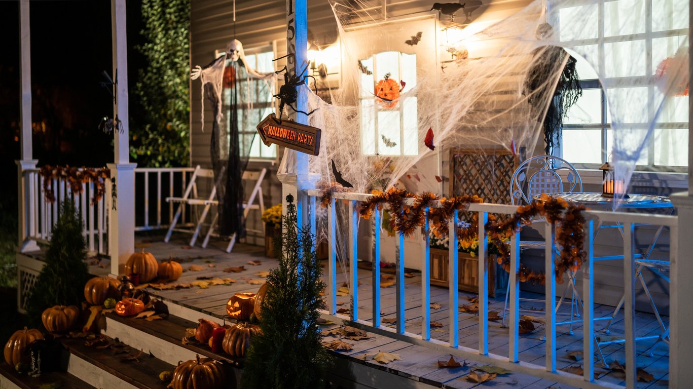 A front porch at dusk decorated with many of the best outdoor Halloween decorations