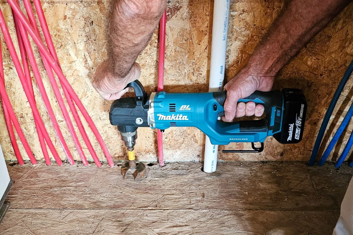 A person using the Makita right-angle drill in a tight space