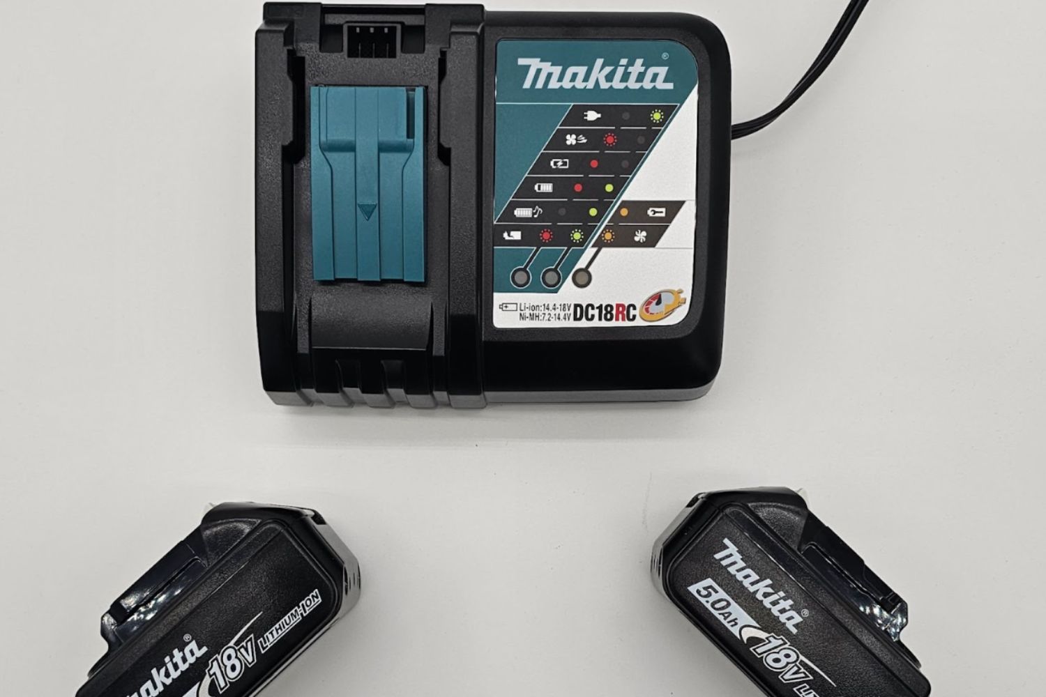 The batteries of the Makita right-angle drill laid out next to their charger