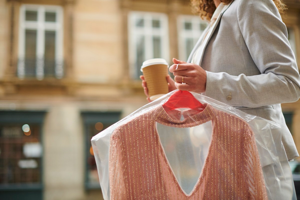 Woman carrying dry cleaning and coffee cup