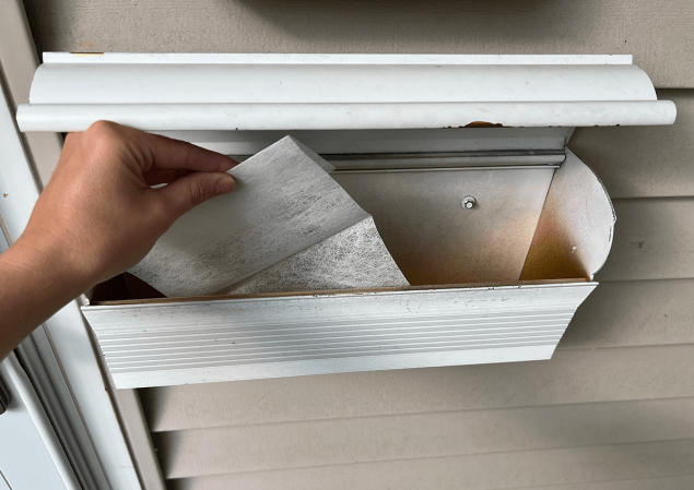 Person putting dryer sheet in an empty mailbox
