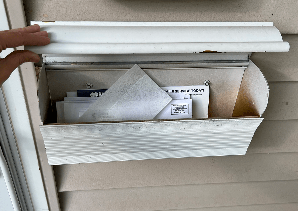 Woman putting dryer sheet in mailbox with mail