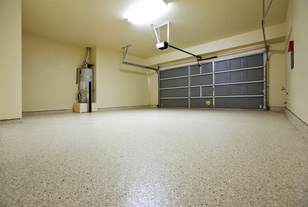 An empty garage with beige epoxy flooring.