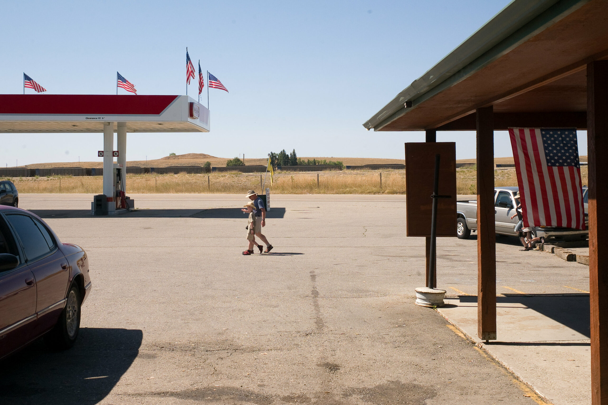 tourists walking outside at a gas station and museum site with American flags at the Little Bighorn site in Garryowen Montana