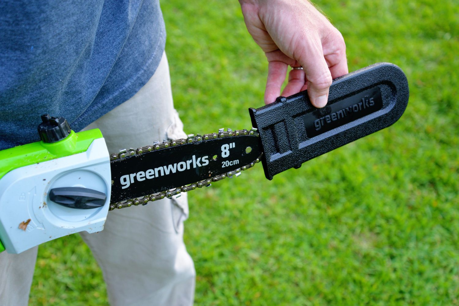 Someone removing the blade guard on the Greenworks 40V cordless pole saw