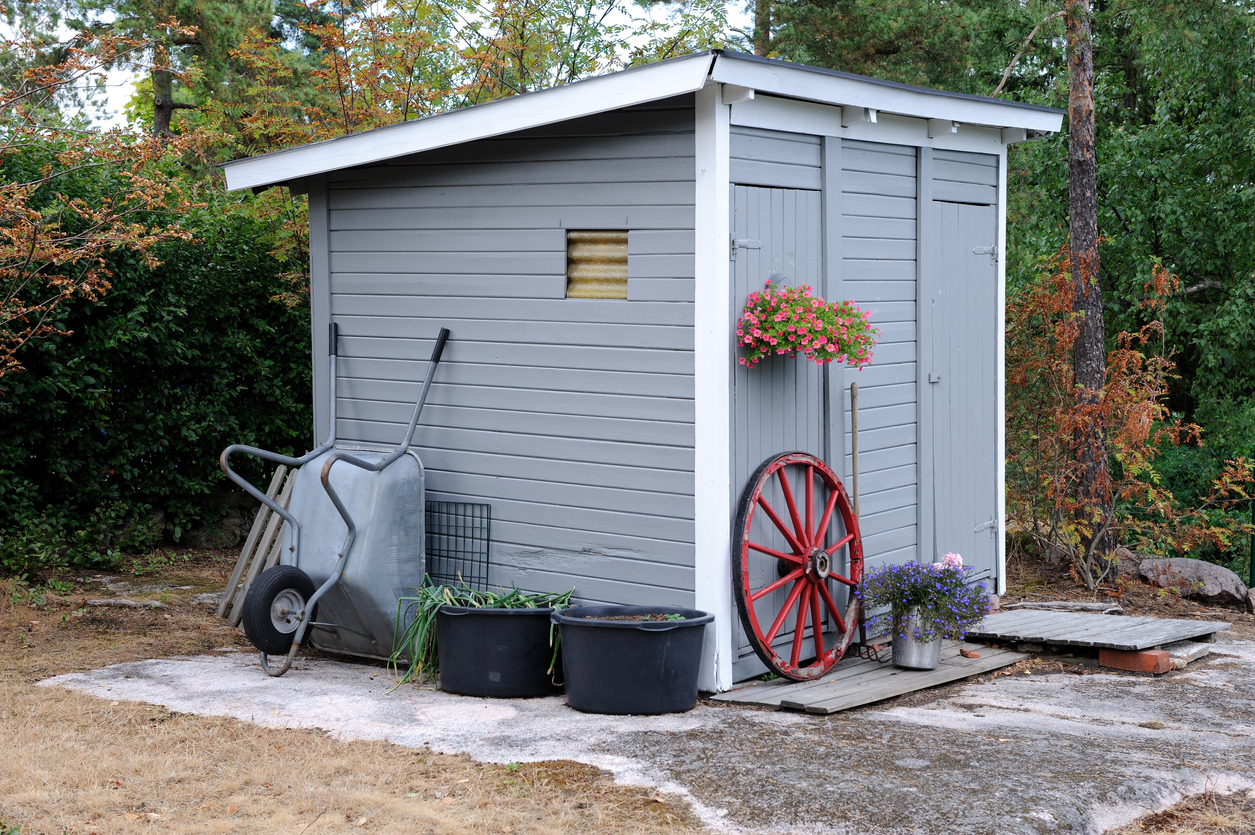 small-grey-storage-shed-with-wheelbarrow-and-flowers