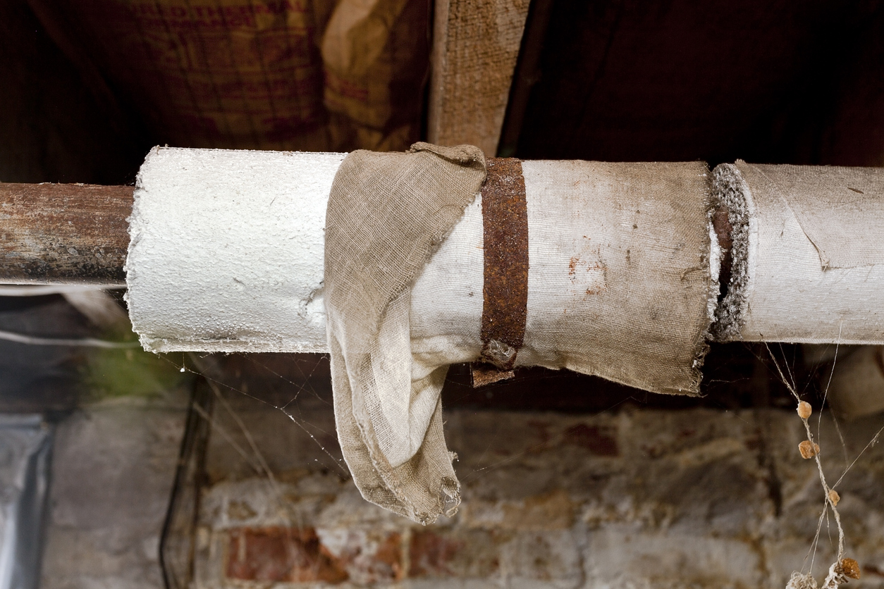 Basement plumbing pipes wrapped with asbestos insulation.