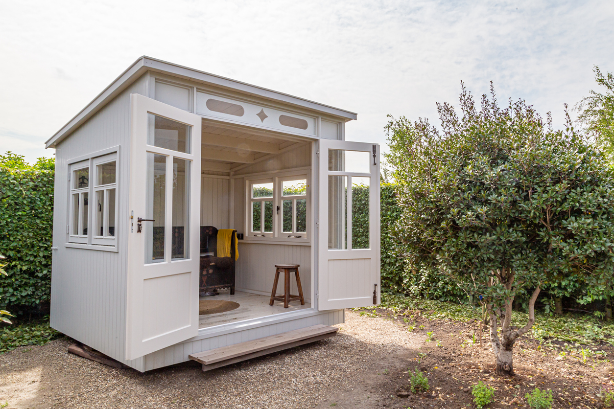 white-shed-with-open-doors-in-a-corner-of-the-yard-on-level-ground