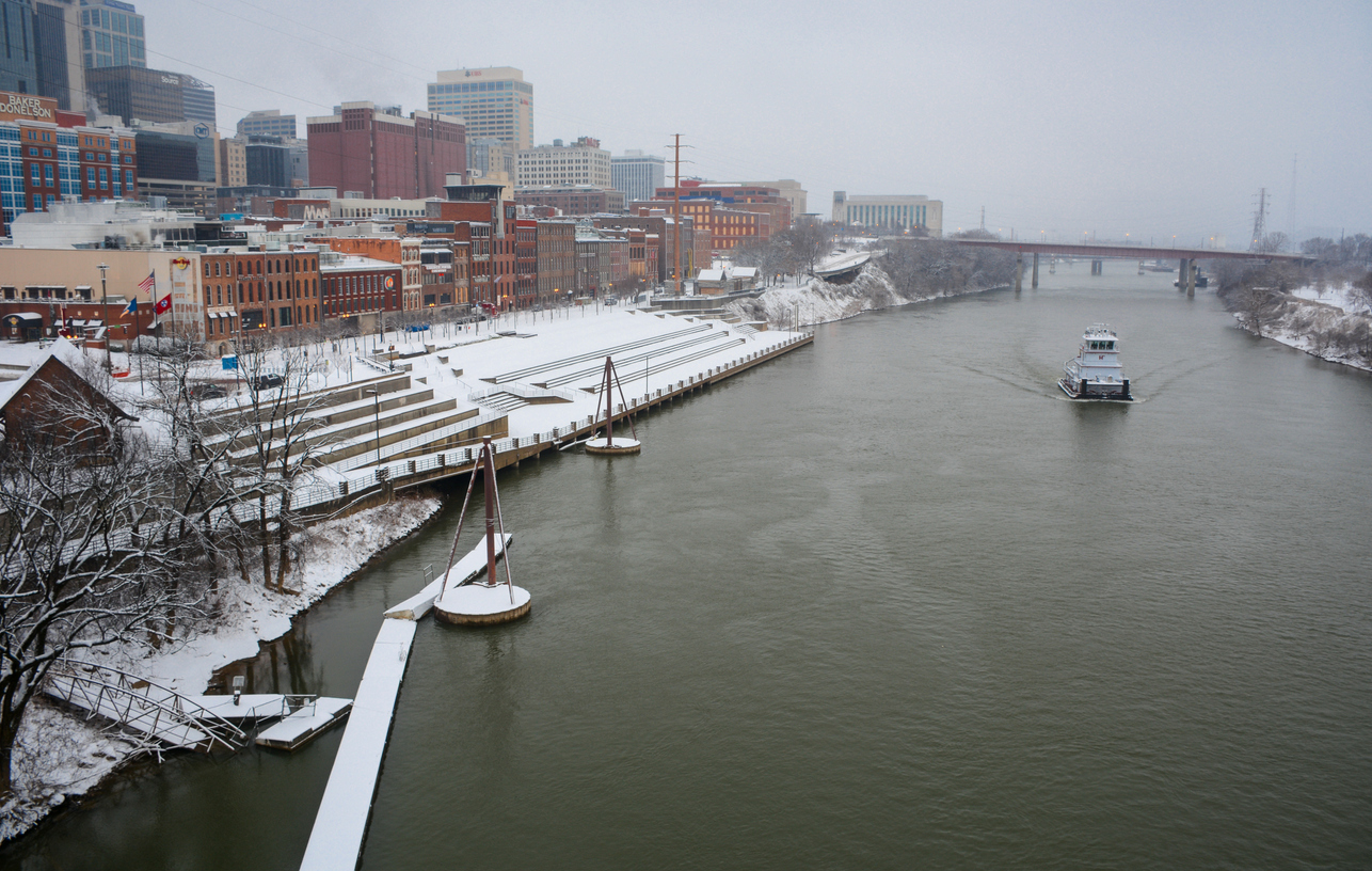 Nashville, TN, 2021: Nashville's Riverfront Park, created in the early 1980s to commemorate Nashville’s river history, is covered in snow as a boat chugs by on the Cumberland River.