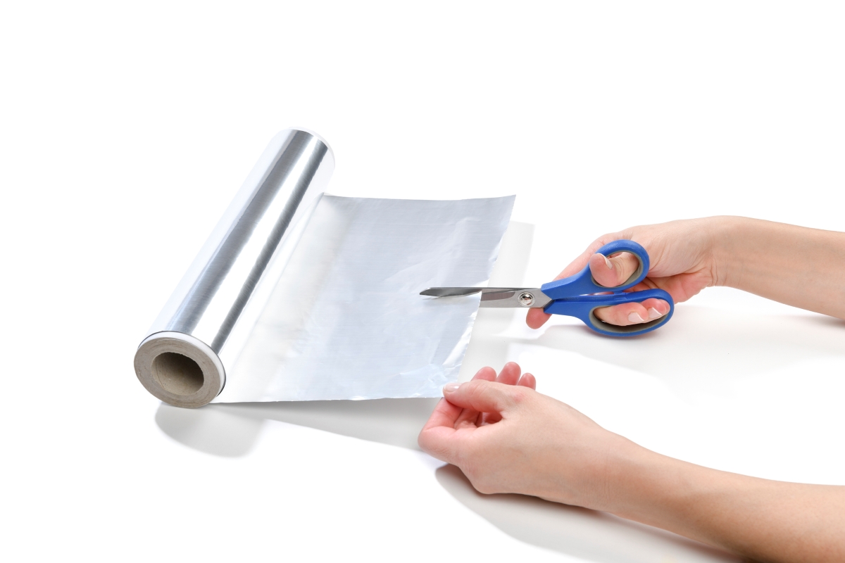 Person cutting aluminum foil with scissors