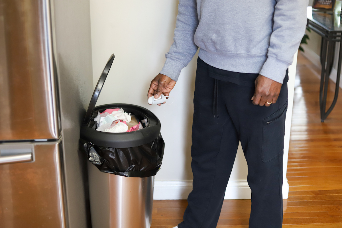 homeowner throwing trash into trash can in kitchen