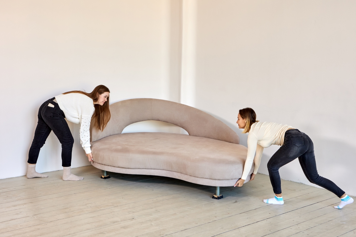 Two women sliding modern couch.