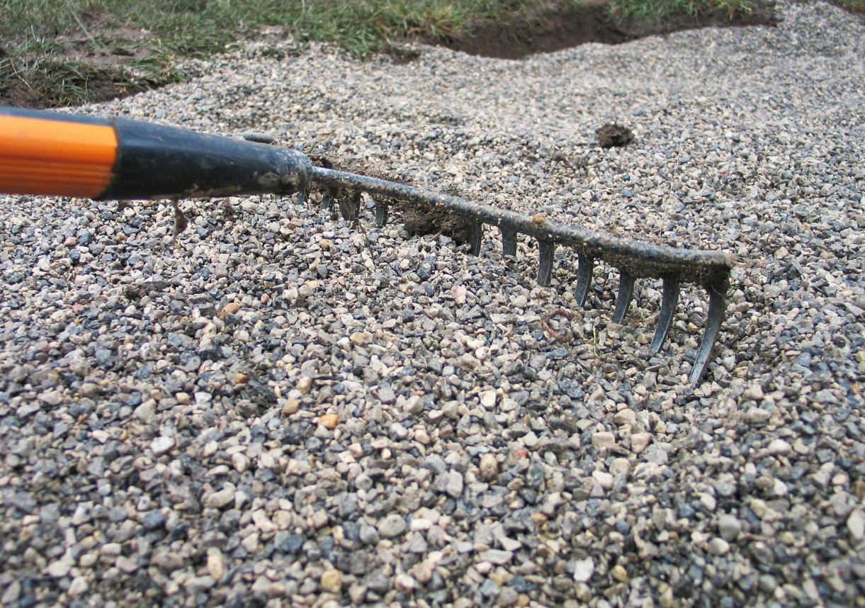 close view of rake being dragged over gravel driveway