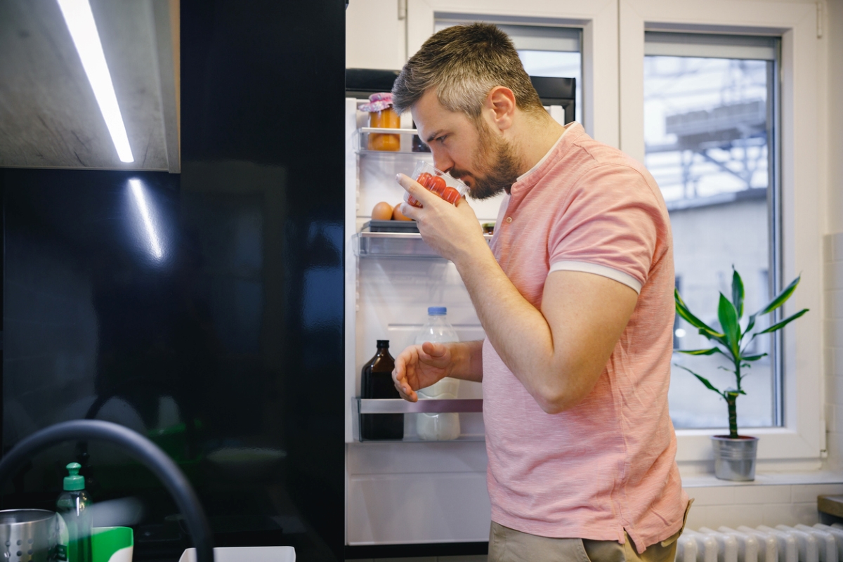 Man smelling tomatoes from fridge