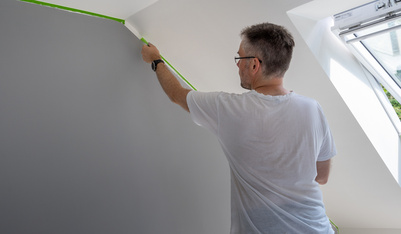 painter removing painters tape from ceiling