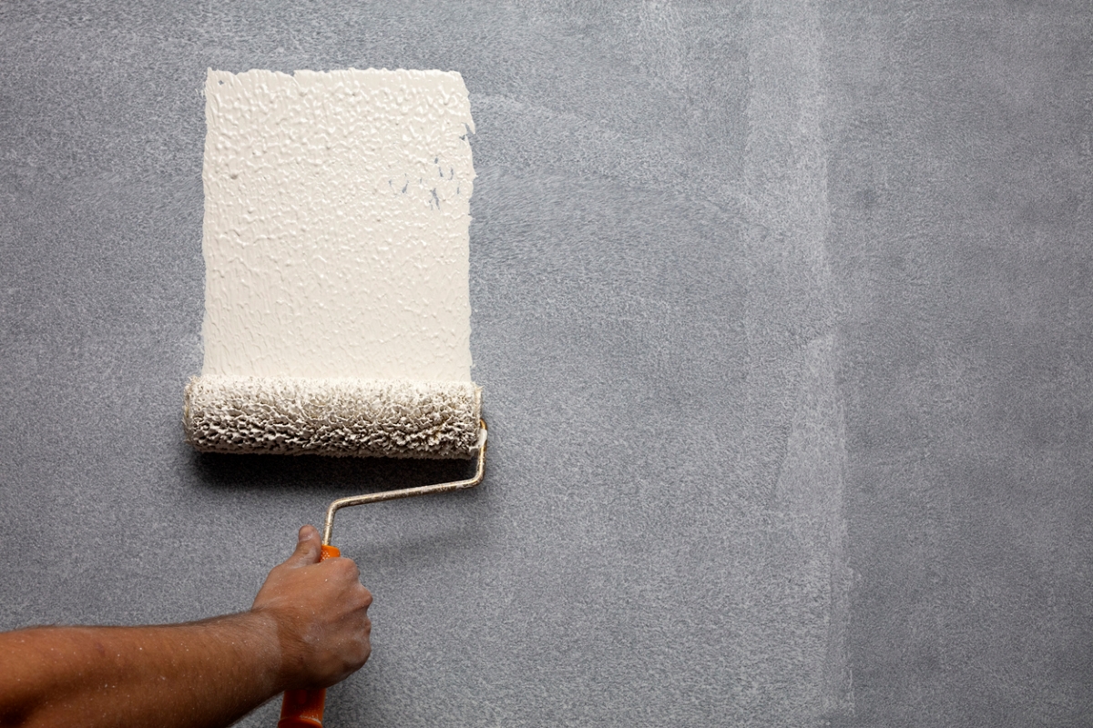 Person using paint roller to paint dark wall