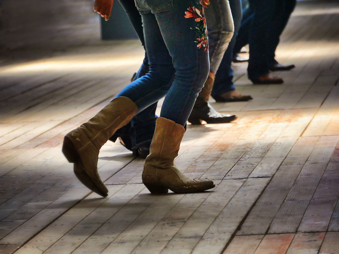 group-with-jeans-and-cowboy-boots-line-dancing-on-a-wooden-floor