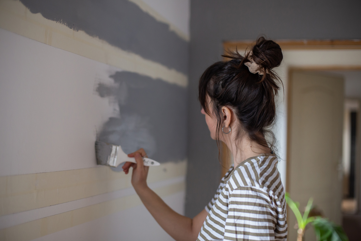 woman painting wall gray with brush marks
