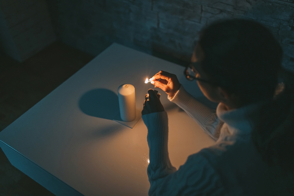 Woman lighting candle at night