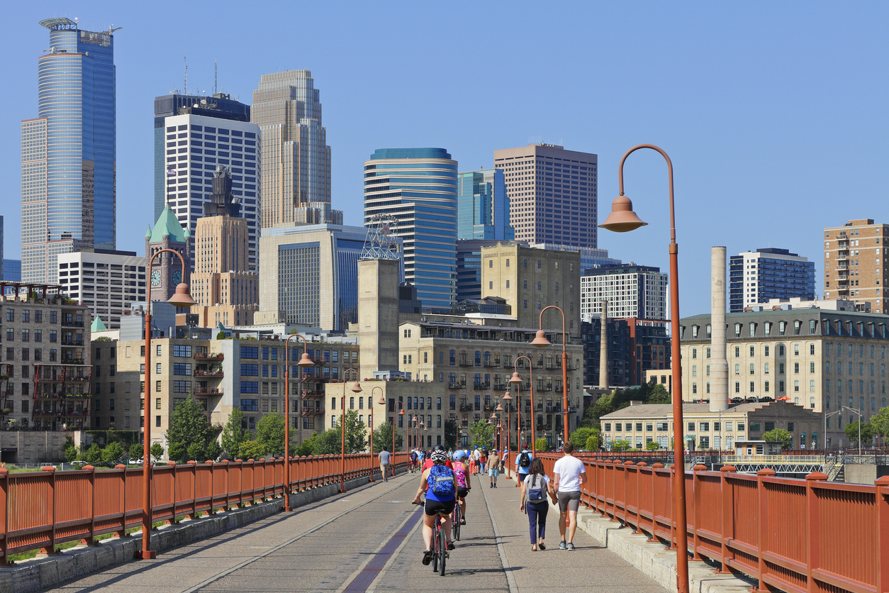 bridge in minneapolis with cyclists and skyline in the background