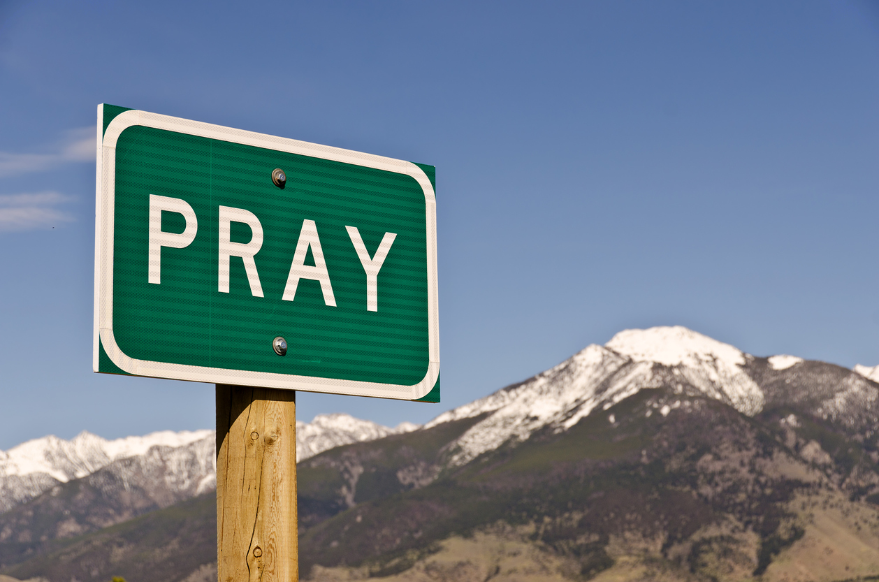 road sign for Pray, Montana in front of mountain