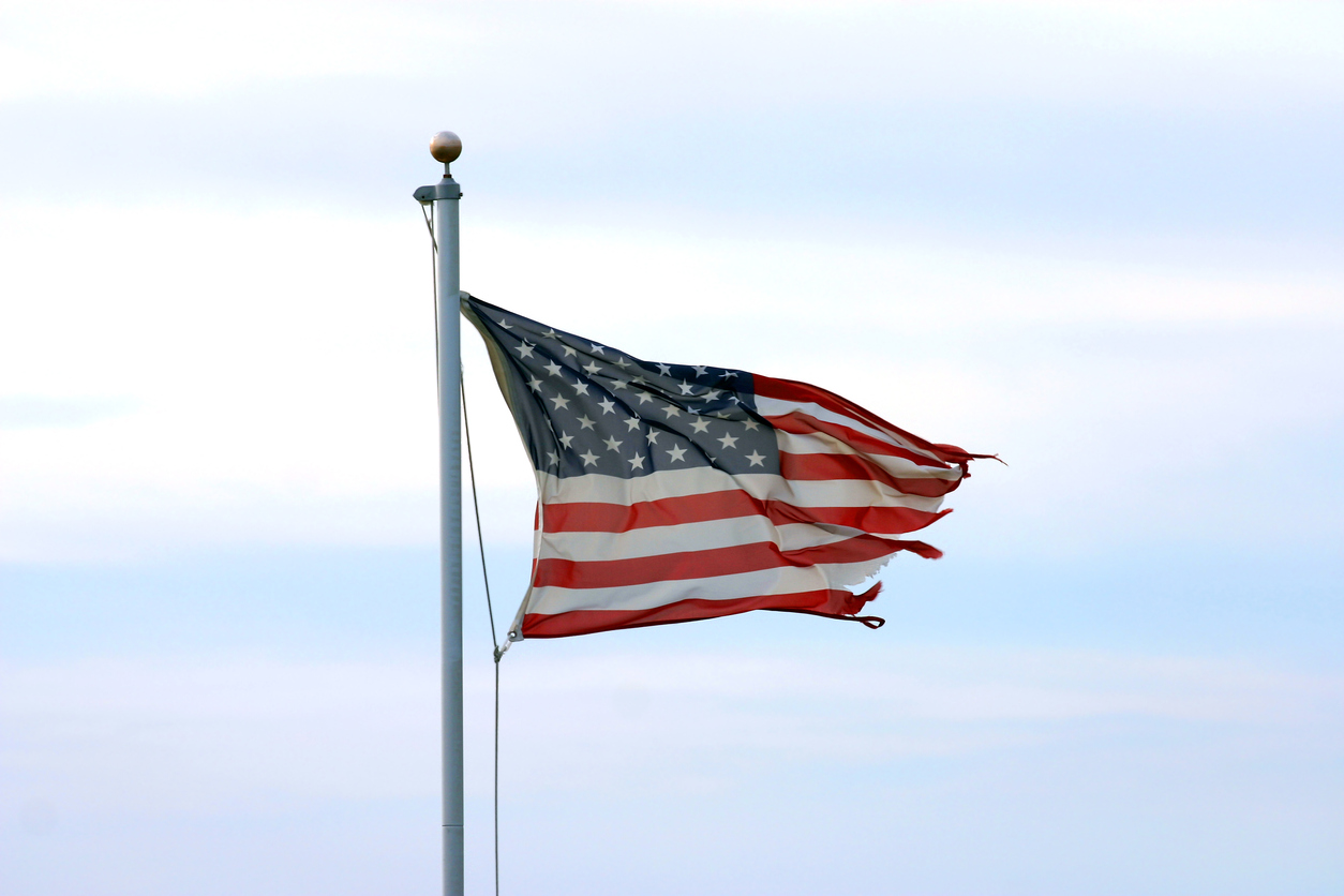 tattered American flag flying against a blue sky