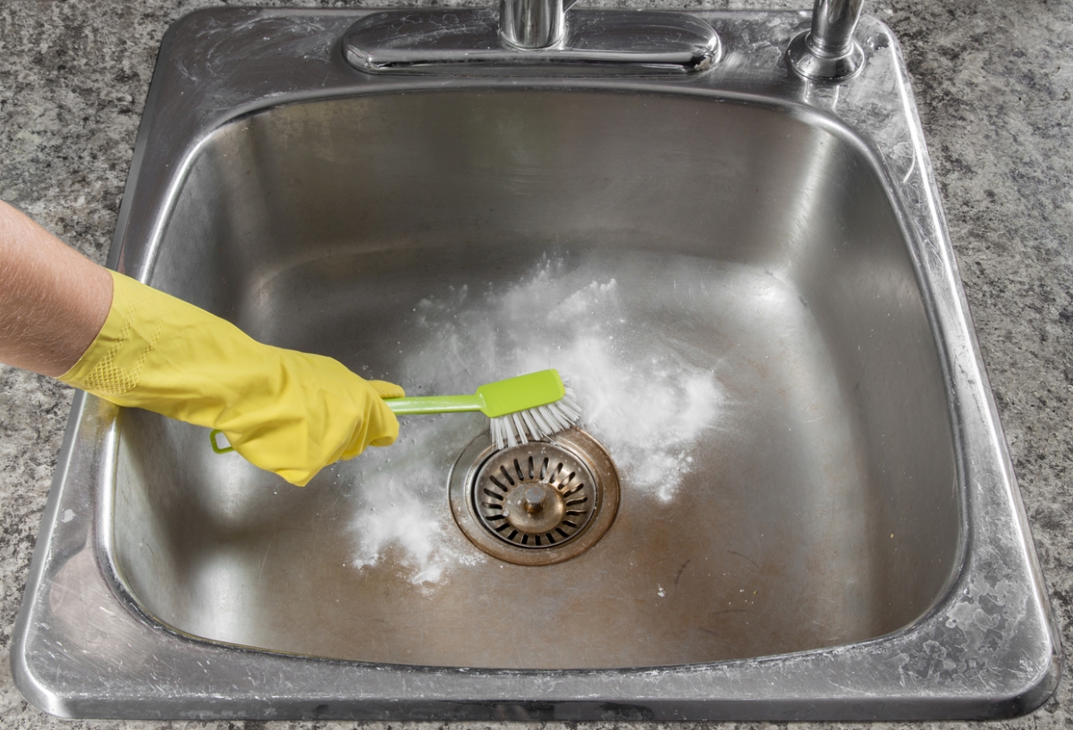 Brush scrubbing kitchen sink with powdered cleaner