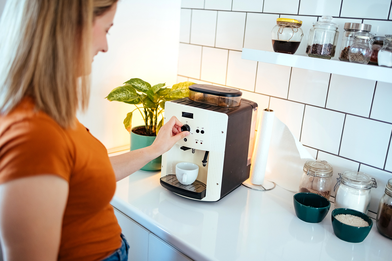 Young woman making coffee on coffee machine at home