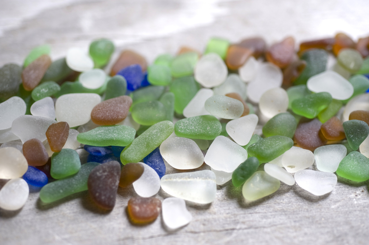 A pile of colorful sea glass on a wooden surface. Sea glass can be found on beaches all over the word and is tumbled smooth by the sea and surf over many years.