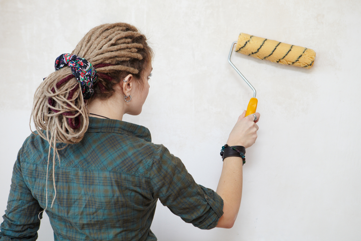 woman priming a wall with a roller