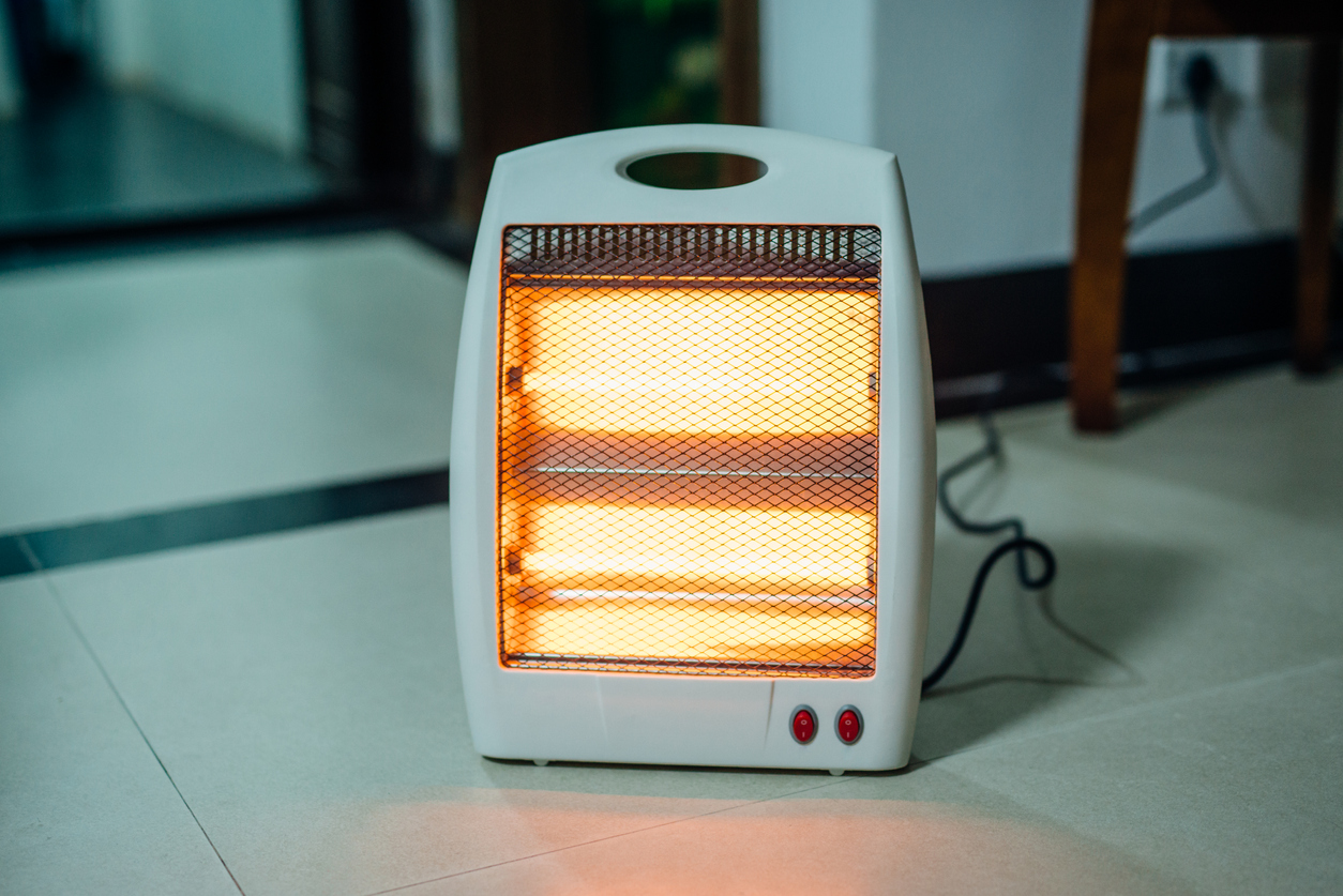 space-heater-with-orange-heat-glow-plugged-into-a-wall-on-the-floor-of-a-home