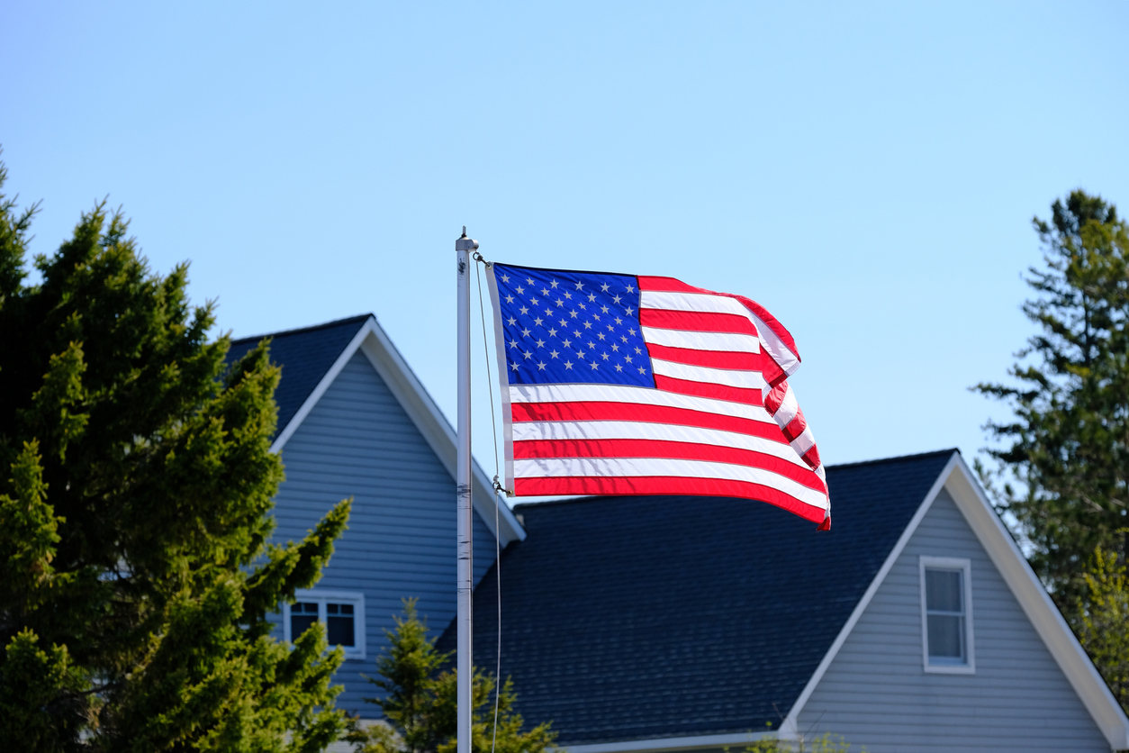 American flag flying in front of top of a large suburban house