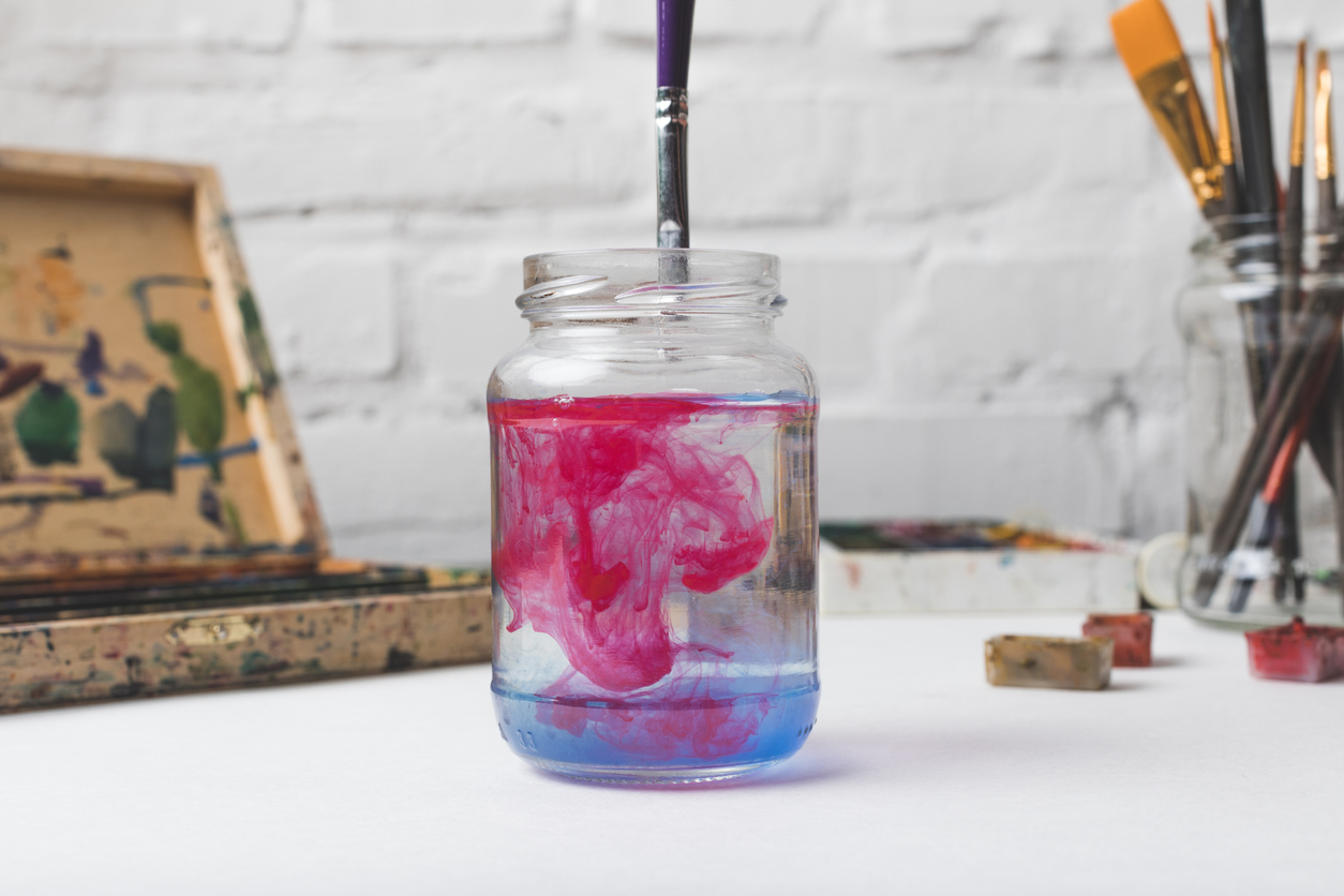 mason jar with water and pink paint from paintbrush