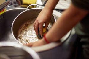 Person scrubbing pot in sink
