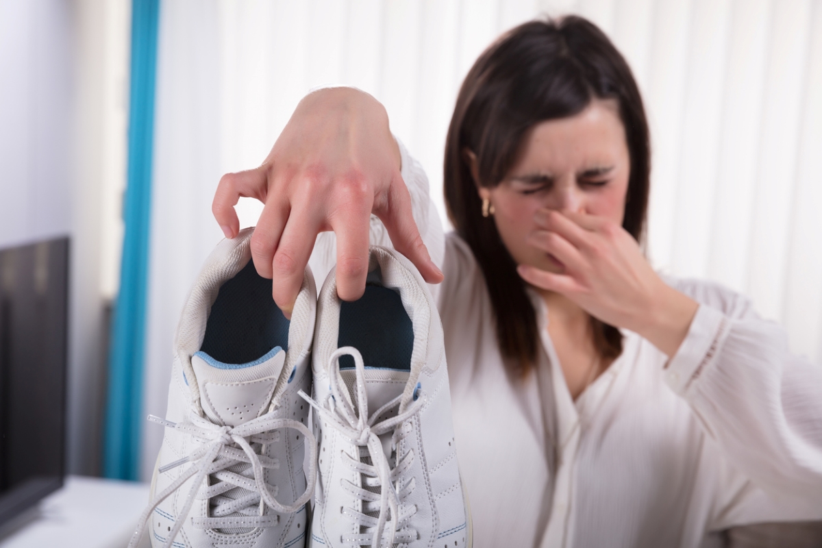 Woman holding stinky shoes and holding her nose