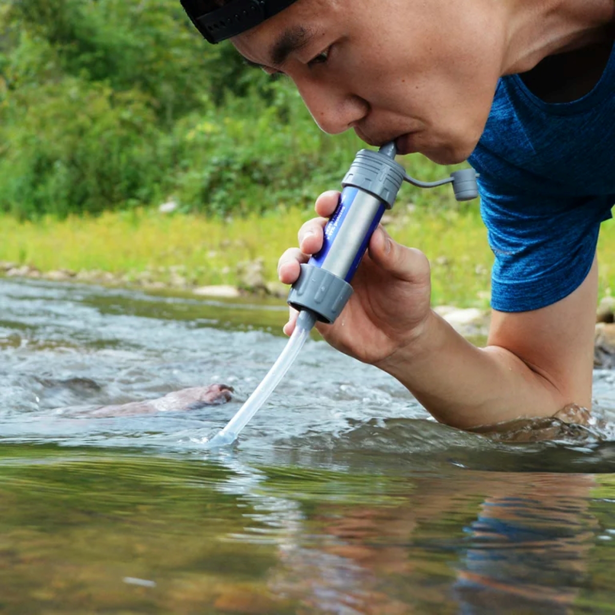 Man using water filter to drink from stream