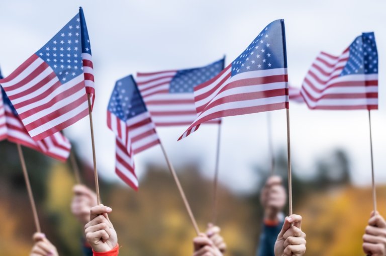Crowd waving small American flags in the air.